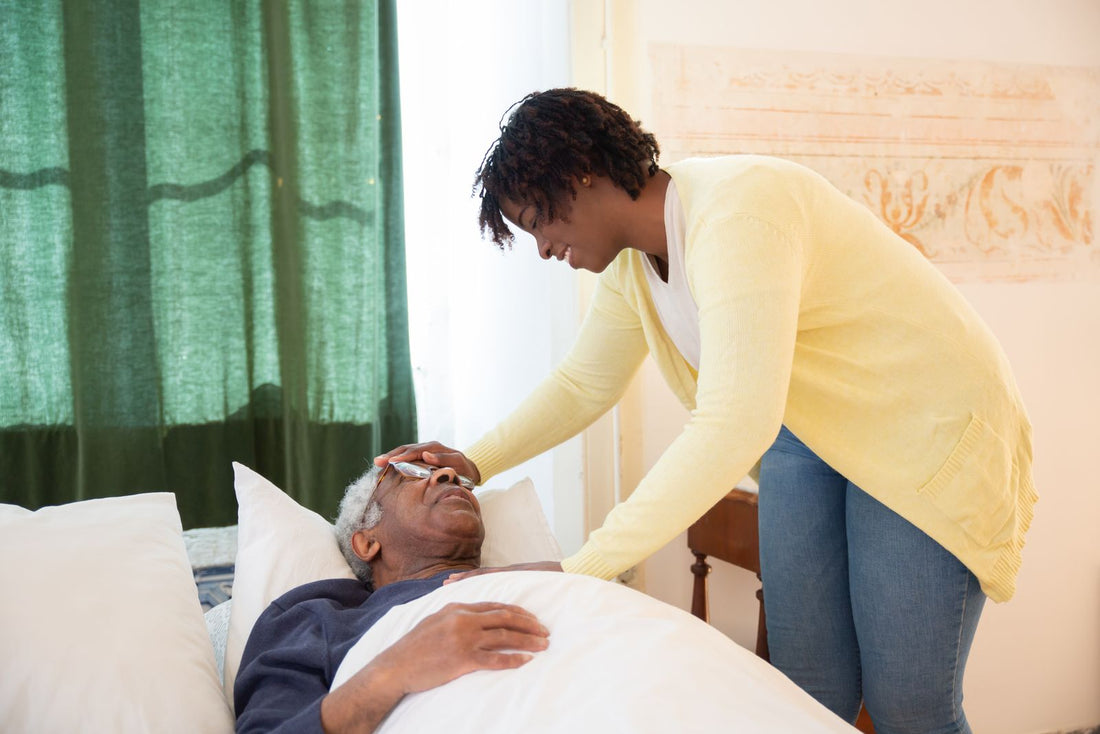 A daughter caring for her elderly father at home, adjusting his glasses as he rests in bed