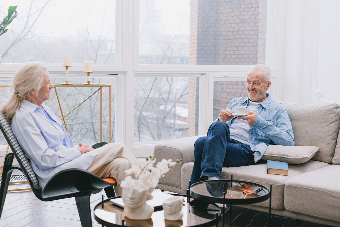 A relaxed senior couple chatting over coffee in a bright living room