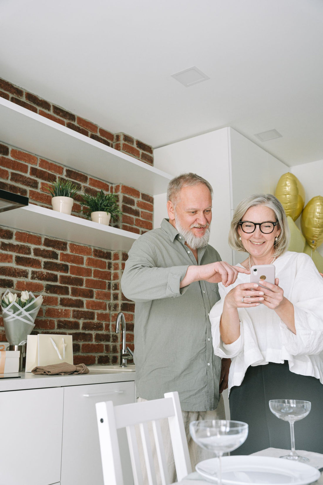 A senior couple comparing product options together on a smartphone in their kitchen